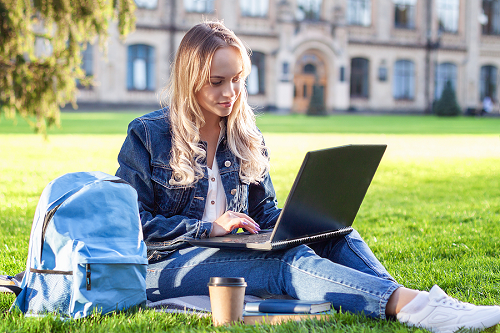 A college student studying on the campus lawn