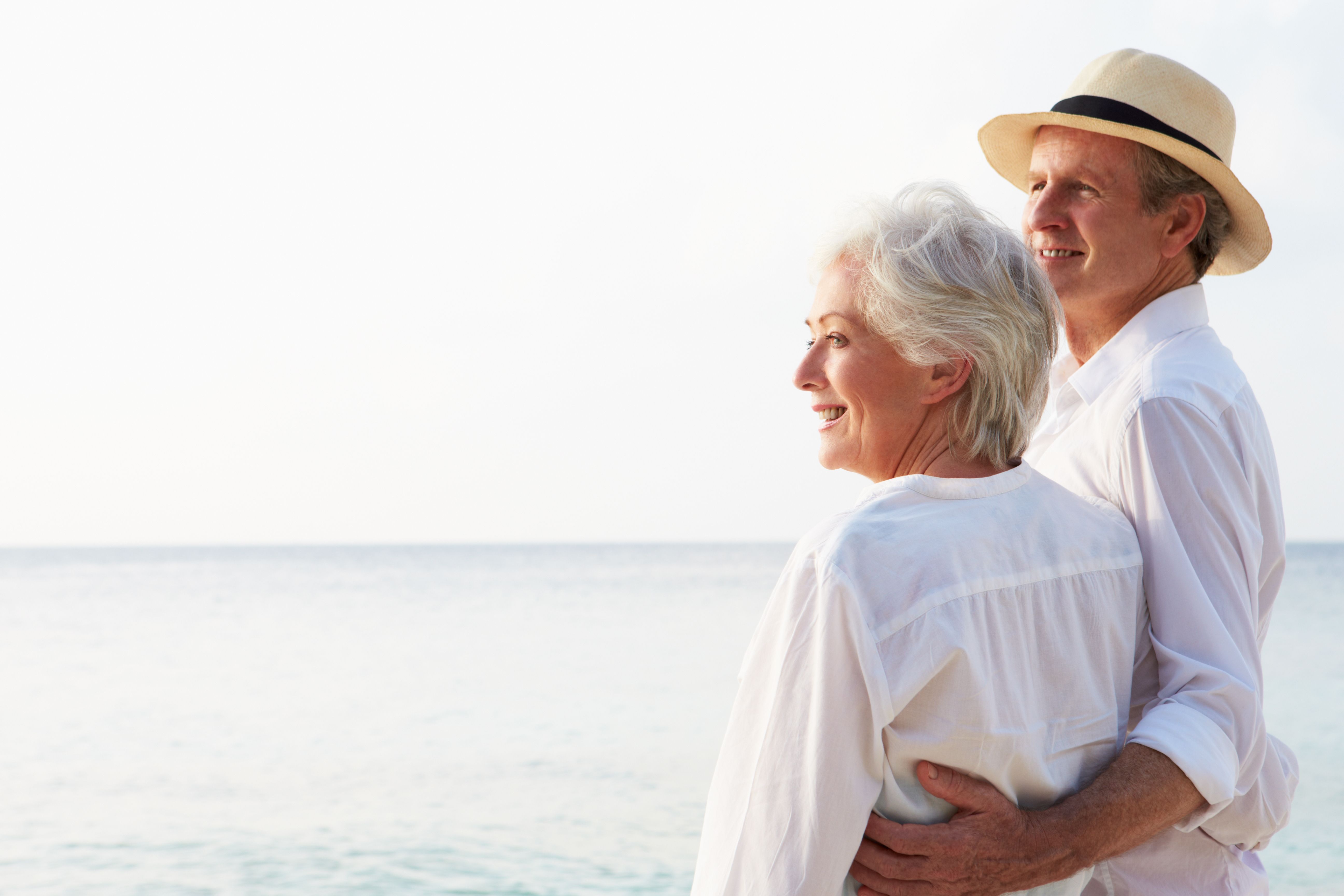 A comfortable, mature couple at their beachfront property looks over the ocean.